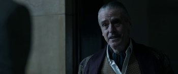 Movie still from “House of Gucci” (2021), directed by Ridley Scott – An older man with a mustache is looking at the camera; Close Up shot, Over the shoulder angle