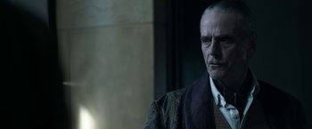 Movie still from “House of Gucci” (2021), directed by Ridley Scott – An older man in a suit and tie looking at the camera; Close Up shot, Over the shoulder angle