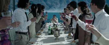 Movie still from “House of Gucci” (2021), directed by Ridley Scott – A group of people sitting at a table drinking wine; Wide shot, High angle