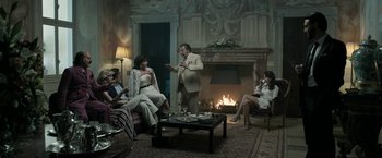 Movie still from “House of Gucci” (2021), directed by Ridley Scott – A group of people sitting in a living room; Wide shot, High angle