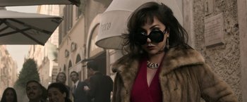 Movie still from “House of Gucci” (2021), directed by Ridley Scott – A woman wearing a fur coat and sunglasses; Medium shot, Over the shoulder angle