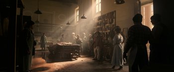 Movie still from “House of Gucci” (2021), directed by Ridley Scott – A group of people standing in a room with sunlight coming through the window; Wide shot, Low angle