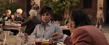 Movie still from “House of Gucci” (2021), directed by Ridley Scott – A woman sitting at a table in front of another woman; Medium shot, Over the shoulder angle