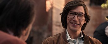 Movie still from “House of Gucci” (2021), directed by Ridley Scott – A person wearing glasses and a jacket; Close Up shot, Over the shoulder angle