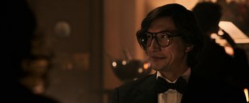 Movie still from “House of Gucci” (2021), directed by Ridley Scott – A person wearing a suit and glasses; Close Up shot, Over the shoulder angle