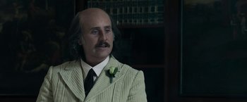 Movie still from “House of Gucci” (2021), directed by Ridley Scott – A man in a suit with a flower in his lapel; Close Up shot, Over the shoulder angle