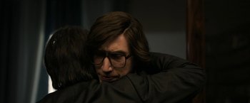 Movie still from “House of Gucci” (2021), directed by Ridley Scott – A man with long hair and glasses hugging another man; Close Up shot, Over the shoulder angle