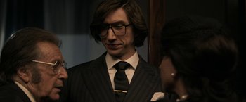 Movie still from “House of Gucci” (2021), directed by Ridley Scott – A man in a suit and tie wearing glasses and a tie; Close Up shot, Over the shoulder angle