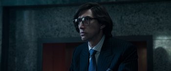 Movie still from “House of Gucci” (2021), directed by Ridley Scott – A man in a suit and tie wearing glasses; Close Up shot, Low angle