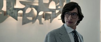 Movie still from “House of Gucci” (2021), directed by Ridley Scott – A man in a suit and glasses standing in front of a wall; Close Up shot, Low angle
