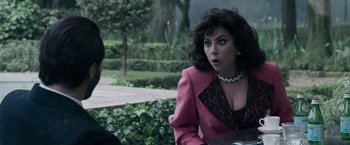 Movie still from “House of Gucci” (2021), directed by Ridley Scott – A woman wearing a pink jacket and a necklace; Close Up shot, Over the shoulder angle