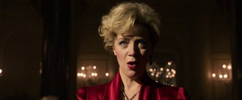 Movie still from “House of Gucci” (2021), directed by Ridley Scott – A woman in a red dress is looking at the camera; Close Up shot, Low angle