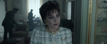 Movie still from “House of Gucci” (2021), directed by Ridley Scott – A person wearing a suit and a necklace; Close Up shot, Over the shoulder angle
