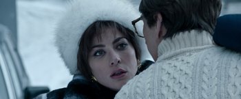 Movie still from “House of Gucci” (2021), directed by Ridley Scott – A woman wearing a white hat looking at another woman; Close Up shot, Over the shoulder angle