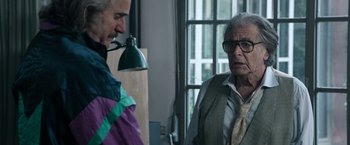 Movie still from “House of Gucci” (2021), directed by Ridley Scott – Two older people are talking in a room; Medium shot, Over the shoulder angle