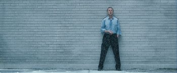 Movie still from “Hunger” (2008), directed by Steve McQueen – A man standing against a brick wall with his hands in his pockets; Wide shot, Low angle