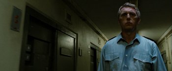 Movie still from “Hunger” (2008), directed by Steve McQueen – A man standing in a hallway next to a door way; Close Up shot, Low angle