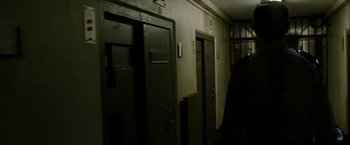 Movie still from “Hunger” (2008), directed by Steve McQueen – A dark room with two doors open and a person standing next to the door; Close Up shot, Low angle