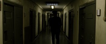 Movie still from “Hunger” (2008), directed by Steve McQueen – A person walking down a hallway in a building; Wide shot, Low angle
