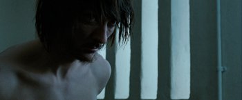 Movie still from “Hunger” (2008), directed by Steve McQueen – A man with long hair and a beard is looking down; Close Up shot, Low angle