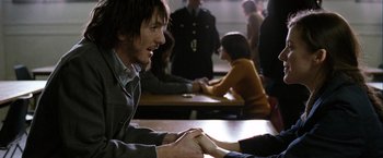 Movie still from “Hunger” (2008), directed by Steve McQueen – A man and a woman sitting at a table with other people; Medium shot, Over the shoulder angle