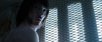 Movie still from “Hunger” (2008), directed by Steve McQueen – A man standing in front of a metal grate; Close Up shot, Over the shoulder angle