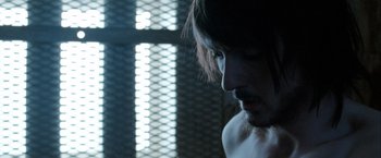 Movie still from “Hunger” (2008), directed by Steve McQueen – A person with a cross in the background; Close Up shot, Over the shoulder angle