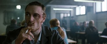 Movie still from “Hunger” (2008), directed by Steve McQueen – A man with bruises on his face sitting at a table; Close Up shot, Over the shoulder angle
