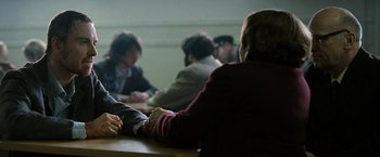 Movie still from “Hunger” (2008), directed by Steve McQueen – A group of people sitting around a table; Medium shot, Over the shoulder angle
