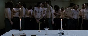 Movie still from “Hunger” (2008), directed by Steve McQueen – A group of men standing around a table with a cross on top of it; Medium shot, High angle