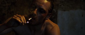 Movie still from “Hunger” (2008), directed by Steve McQueen – A shirtless man smoking a cigarette in a dark room; Close Up shot, Low angle