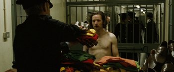 Movie still from “Hunger” (2008), directed by Steve McQueen – A man in a jail cell holding a cup; Medium shot, Over the shoulder angle