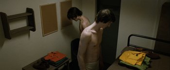 Movie still from “Hunger” (2008), directed by Steve McQueen – Two young men are standing in a bathroom; Medium shot, Over the shoulder angle