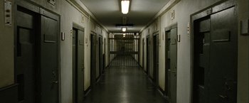 Movie still from “Hunger” (2008), directed by Steve McQueen – A hallway with many doors leading to a jail cell; Extreme Wide shot, High angle