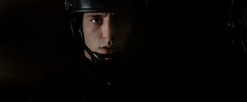 Movie still from “Hunger” (2008), directed by Steve McQueen – A man wearing a helmet in a dark room; Close Up shot, Low angle