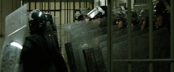 Movie still from “Hunger” (2008), directed by Steve McQueen – A group of people standing next to each other in front of a fence; Medium shot, Over the shoulder angle