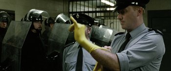 Movie still from “Hunger” (2008), directed by Steve McQueen – A man in a yellow rubber glove and a man in a black shirt and yellow gloves; Medium shot, Low angle