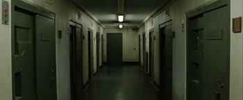 Movie still from “Hunger” (2008), directed by Steve McQueen – A hallway with a door open and a light on the ceiling; Wide shot, High angle