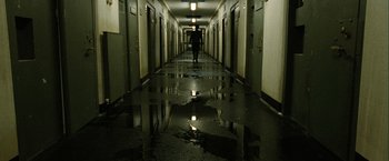 Movie still from “Hunger” (2008), directed by Steve McQueen – A person is walking down a hallway in a building; Wide shot, High angle
