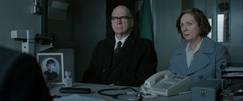 Movie still from “Hunger” (2008), directed by Steve McQueen – A man sitting at a table with a phone and stethoscope on it; Medium shot, Low angle