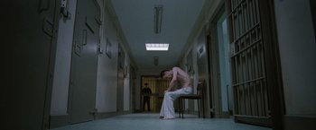 Movie still from “Hunger” (2008), directed by Steve McQueen – A man sitting on top of a chair in a hallway; Wide shot, High angle