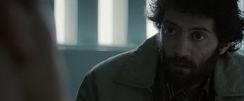 Movie still from “Hunger” (2008), directed by Steve McQueen – A man with a beard is sitting in front of a window; Close Up shot, Over the shoulder angle