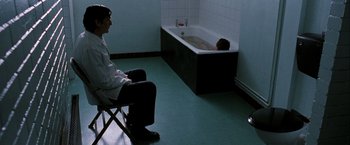 Movie still from “Hunger” (2008), directed by Steve McQueen – A man sitting in a chair in front of a bathtub; Wide shot, High angle