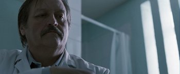 Movie still from “Hunger” (2008), directed by Steve McQueen – An older man sitting in a chair in front of a window; Close Up shot, Low angle