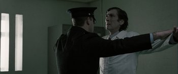 Movie still from “Hunger” (2008), directed by Steve McQueen – A man in a white shirt and a man in a black hat; Medium shot, Over the shoulder angle