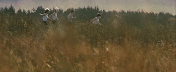 Movie still from “Hunger” (2008), directed by Steve McQueen – A group of people running through a field of tall grass; Wide shot, High angle