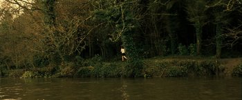 Movie still from “Hunger” (2008), directed by Steve McQueen – A person standing on a tree near a body of water; Extreme Wide shot, High angle