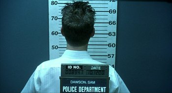 Movie still from “I Am Sam” (2001), directed by Jessie Nelson – A man with his back to the camera and his head in a police officer's uniform; Medium shot, Low angle