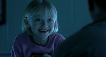 Movie still from “I Am Sam” (2001), directed by Jessie Nelson – A little girl smiling for the camera in the dark; Close Up shot, Over the shoulder angle