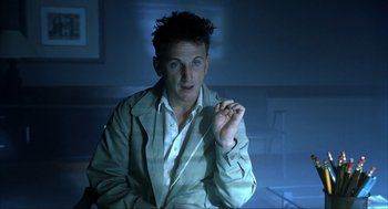 Movie still from “I Am Sam” (2001), directed by Jessie Nelson – A man sitting in front of a camera in a dark room; Close Up shot, Low angle